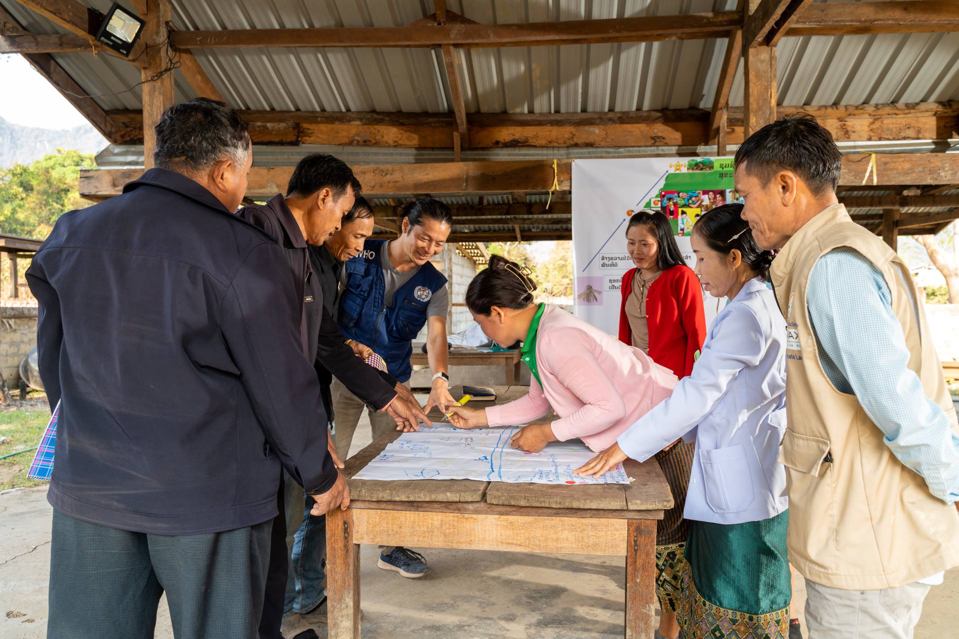 Health workers stand around a table and map out village health services